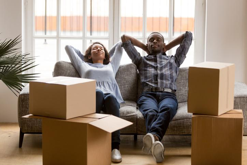 Couple relaxing on couch next to storage boxes.