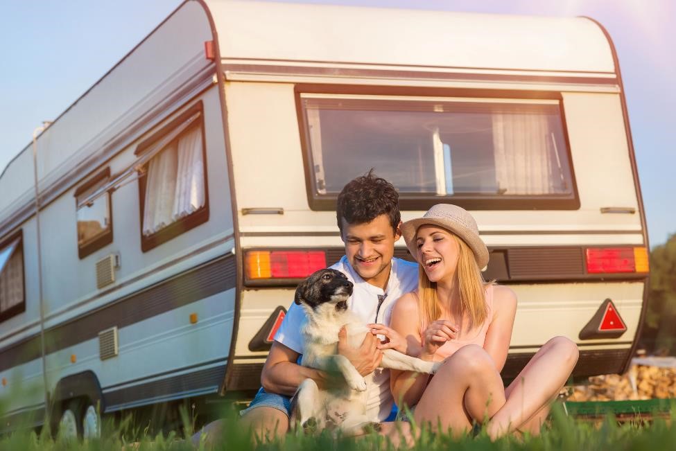 Couple and a dog relaxing and smiling in front of RV.