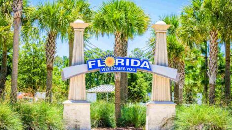 A “Florida welcomes you” sign surrounded by palm trees