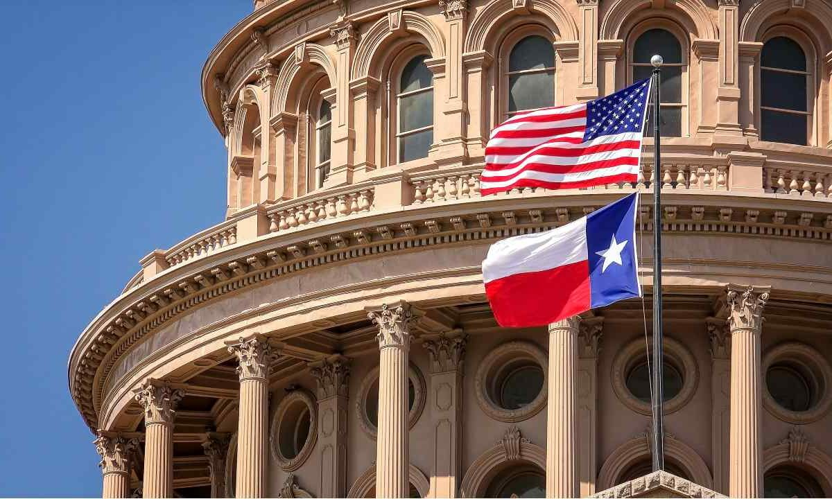 The American and Texas flags fly in front of the Texas capitol building