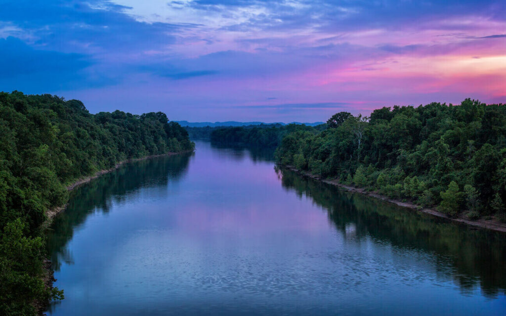 The Cumberland River with trees on either side and a sunset