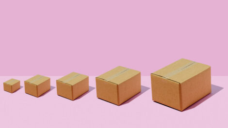 Differently sized sealed boxes next to one another in ascending order against a pink background.
