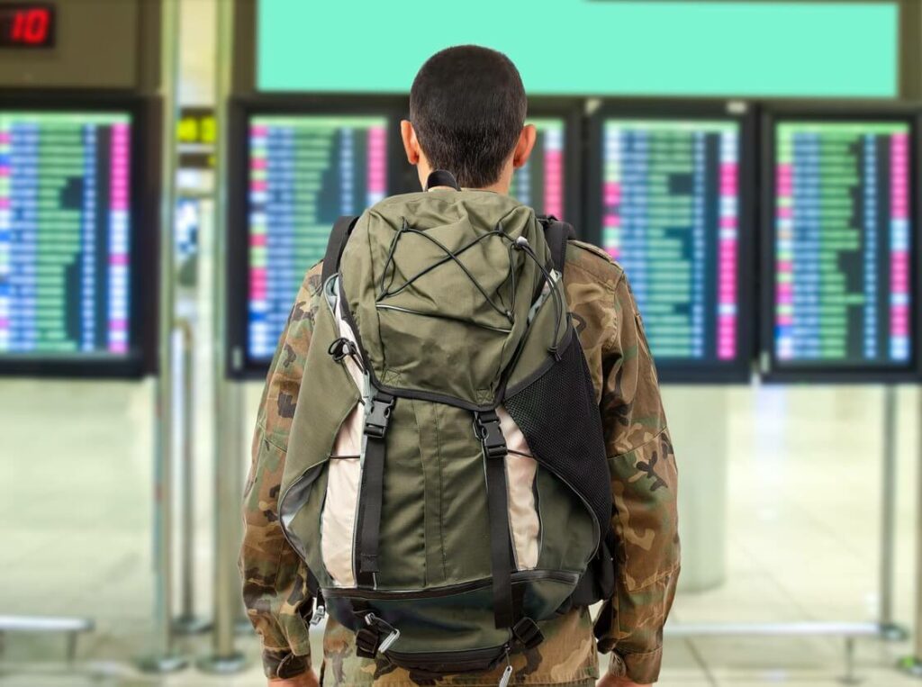 Military personnel standing in an airport checking flight times.